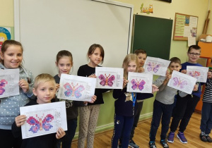 Grupa dzieci prezentuje kolorowe motyle.