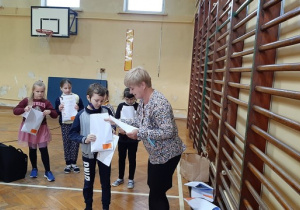 Nauczycielka wręcza dzieciom dyplom za udział w konkursie.