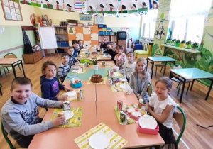 Zdjęcie przedstawia uczniów siedzących przy wielkanocnym stole.