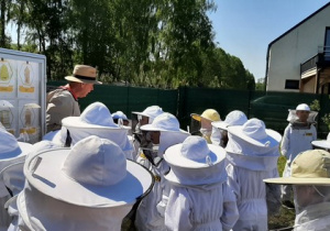Uczniowie na ścieżce edukacyjnej słuchają opowiadań pszczelarza