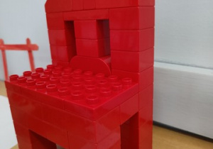 Czerwone krzesła wykonane przez uczniów. W tle instrukcja obsługi.