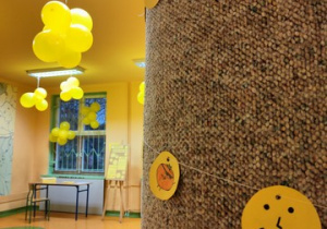 Zdjęcie przedstawia korytarz szkolne. Na pierwszym planie żółte buźki, w tle żółte balony.